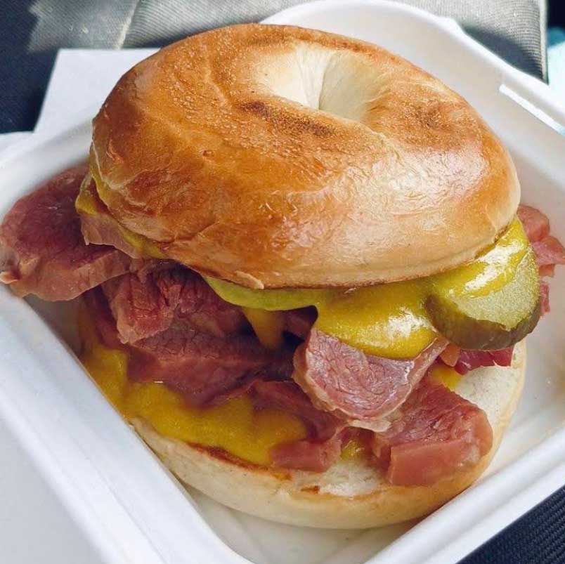 Honywood Sandwich Shop salt beef bagel with thick meat, yellow mustard and a gherkin.