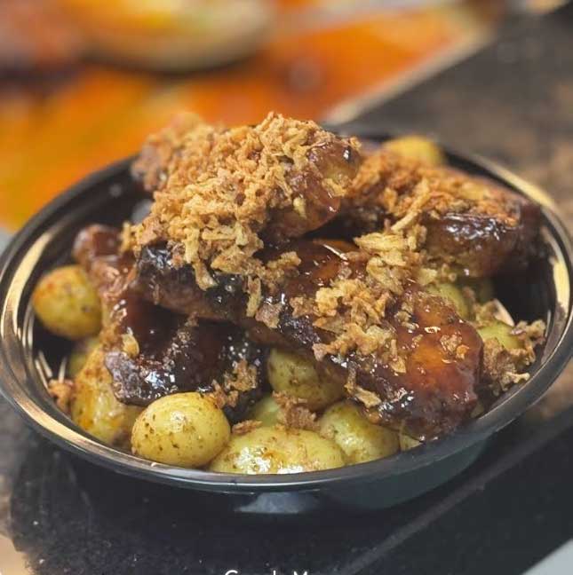 Honywood Sandwich Shop Glazed Pork Belly served over small potatoes, topped with crispy onions.